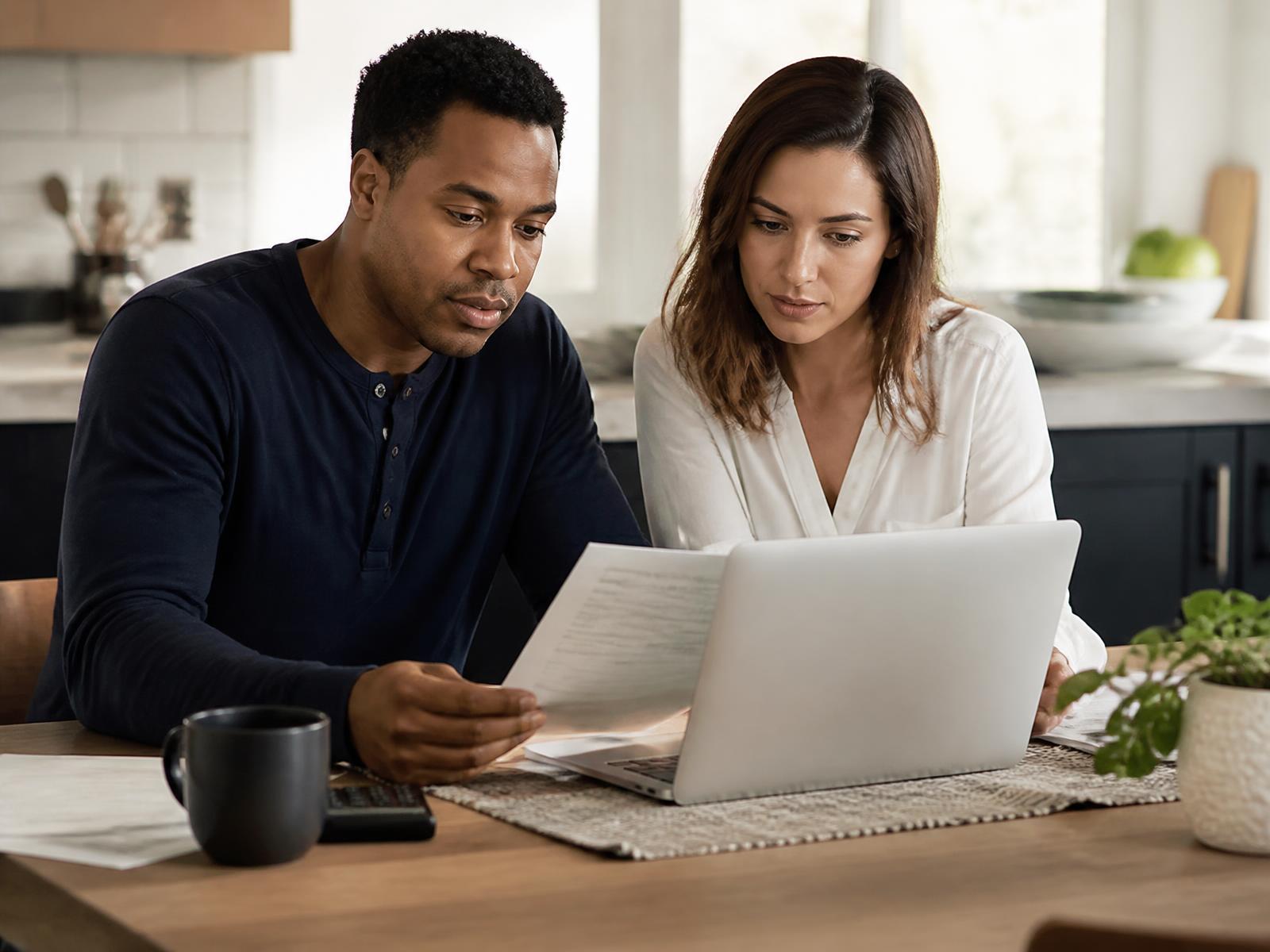 Two people reviewing home-financing paperwork together at a kitchen table